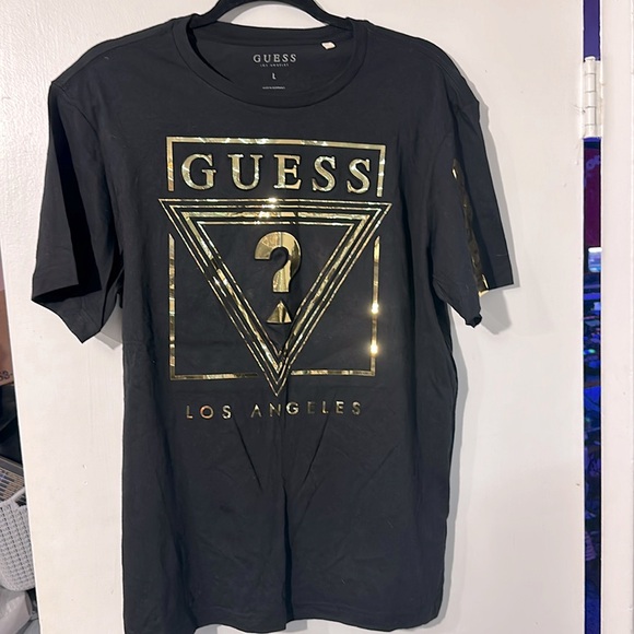 Guess Tops - NWOT. Woman’s Guess black and gold T shirt in size L.
